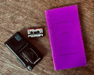 Foto eines Buches, eines Diktiergeräts und einer Kassette